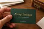 Hand holding a personalized bottle-green Avery Bennett business card with a raised gold-foil name