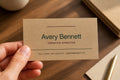 Hand holding a personalized Avery Bennett business card printed in dark inks on natural kraft stock