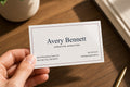 Hand holding a personalized Avery Bennett business card printed on smooth white 14 pt gloss stock