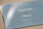 Macro close-up of the Madeline and Owen postcard showing a broad reflection across the glossy blue front